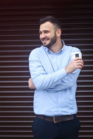 Portrait of a businessman, manager on a striped wall background. Bearded sexy man singing coffee, tea. Stock photosの写真素材
