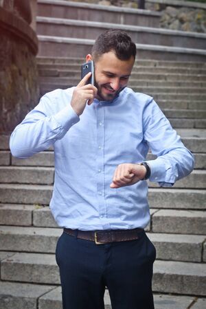 Portrait of a bearded man near the big steps of an old European castle. Businessman talking on the phone. Fashionable guy with stylish clothes.の写真素材