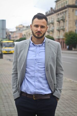 Portrait of a businessman on the street near the road of a European city. A bearded handsome man dressed stylishly. Fashionable guy hipster. Stock photosの写真素材
