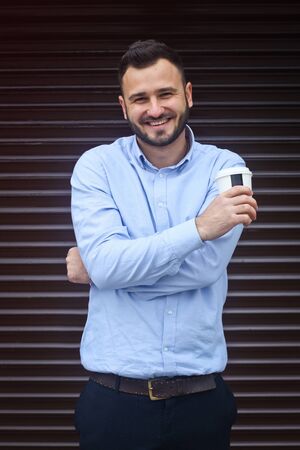 Portrait of a businessman, manager on a striped wall background. Bearded sexy man singing coffee, tea. Stock photosの写真素材