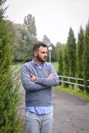 Young guy on the background of European, American city. man in the background of trees and fields and fence. The owner of a beautiful land for businessの写真素材