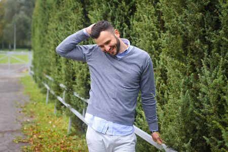 Young guy on the background of European, American city. man in the background of trees and fields and fence. The owner of a beautiful land for businessの写真素材