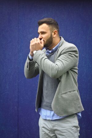 Fashionably dressed man against a blue wall. Cold winter, autumn weather. A warming guy. Stock Photo for designの写真素材