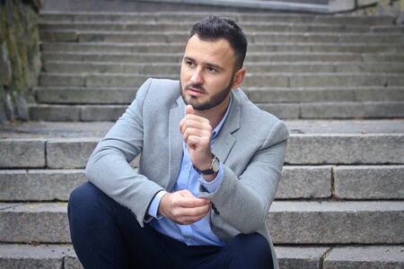 Portrait of a bearded man near the big steps of an old European castle. Businessman thinking over a future project. Fashionable guy with stylish clothes.の写真素材