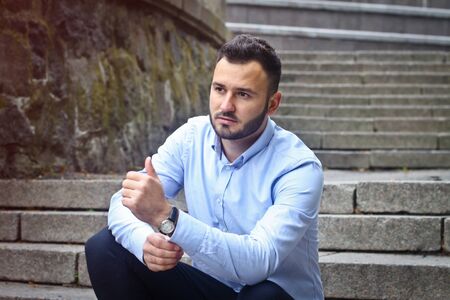 Portrait of a bearded man near the big steps of an old European castle. Businessman thinking over a future project. Fashionable guy with stylish clothes.の写真素材