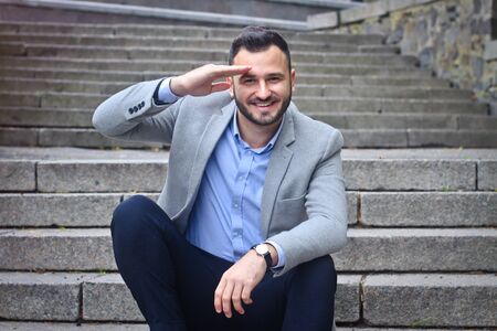 Portrait of a bearded man near the big steps of an old European castle. Businessman thinking over a future project. Fashionable guy with stylish clothes.の写真素材