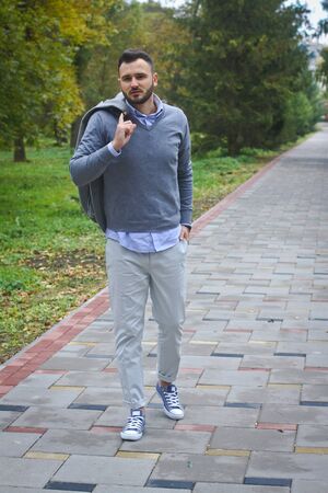 Young sexy guy strolling through the autumn, summer park. man drinking coffee, tea in the nature. European countryside. Stock Photo for designの写真素材