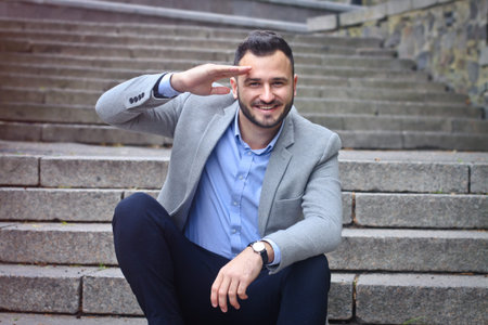 Portrait of a bearded man near the big steps of an old European castle. Businessman thinking over a future project. Fashionable guy with stylish clothes.の写真素材