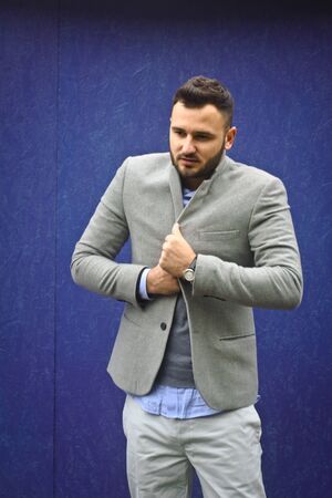 Fashionably dressed man against a blue wall. Cold winter, autumn weather. A warming guy. Stock Photo for designの写真素材