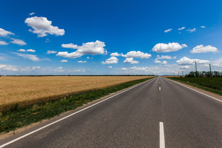 Blue sky with clouds over asphalt roadの写真素材