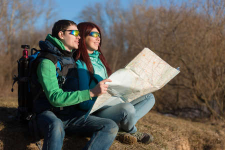 Young couple hiking with backpacks sitting on grass.の写真素材