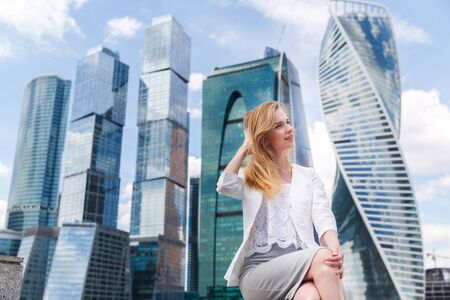 Young woman sitting against office buildings.の写真素材