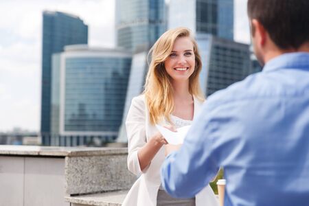 Close-up of handing over documents during business briefing in city streetの写真素材