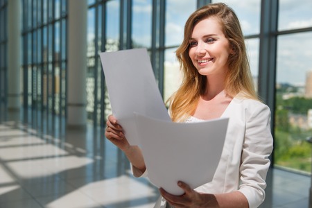 Businesswoman hold some documents against a big windowの写真素材