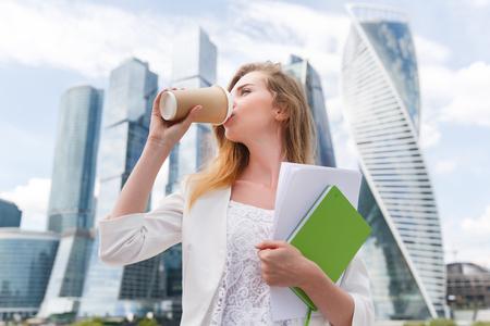 Young stylish woman drinking coffee to go in a city streetの写真素材