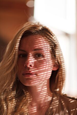Portrait of young beautiful woman with striped shadow on face.の写真素材