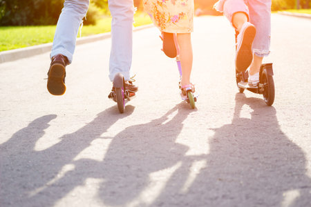 Parents with kid riding scooters in summer. Closeup image with legs.