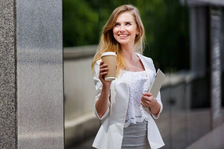 Young stylish woman drinking coffee to go in a city streetの写真素材