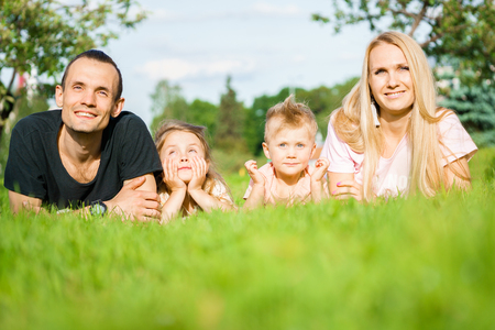 Portrait of happy parents and kids lying at the parkの写真素材