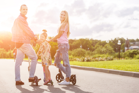 Family with scooters in the park. lens flare effectの写真素材