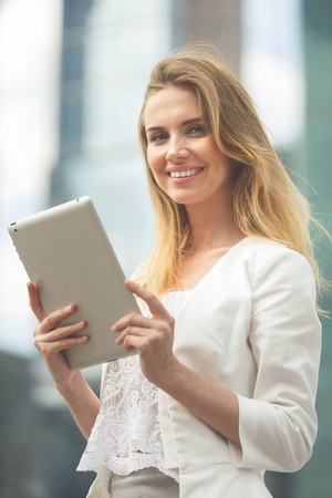 Beautiful woman using electronic tab in the street. Image toned in low contrast.の写真素材
