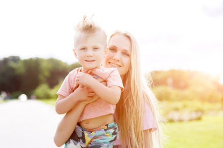 attractive girl playing with his son in the park. lens flare effectの写真素材