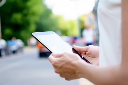 Female hands holding tablet on urban background. Taken with fast apertureの写真素材