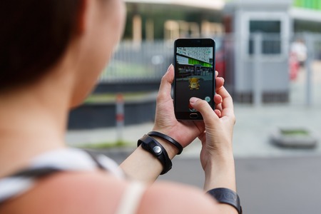 Man held phone in one hand showing its screen with Pokemon Go application on city backgroud. Moscow, Russia.のeditorial素材