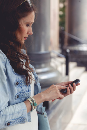 Portrait in profile brunette woman touching screen her smartphone outdoors