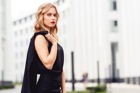 Business lady in black dress posing in middle of business centerの写真素材