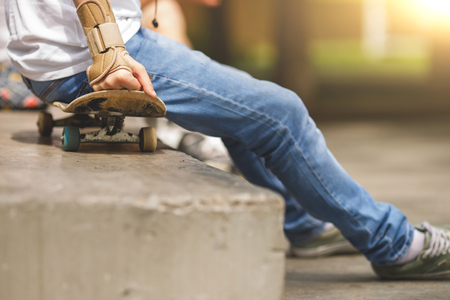 Man sitting in park on skateboard with hand protection. Image with lens flare effectの写真素材
