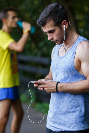 Two young athlete in park relaxing after workout in summerの写真素材