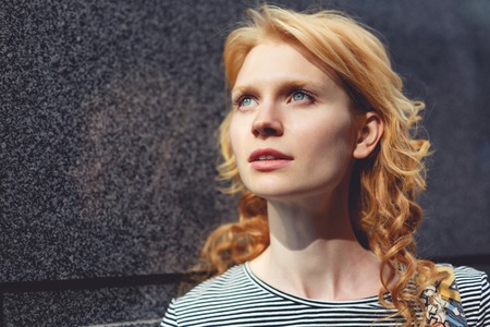 Ginger girl close-up near gray marble wall, tinted photoの写真素材