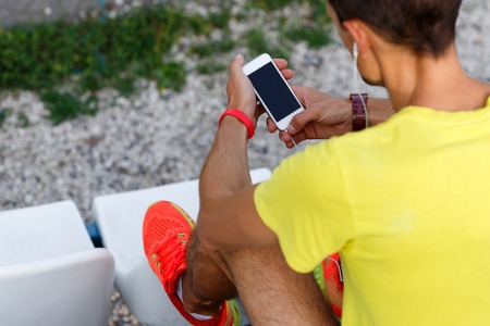 Young athlete holding cell phone while listening music in parkの写真素材