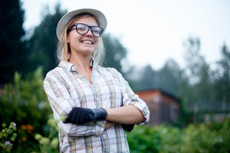Portrait of happy smiling young woman gardener with gloves standing in the middle of her possessionsの写真素材