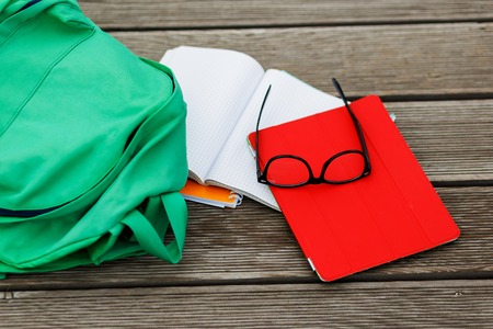 Items for pupil-tablet, notebook, sunglasses, backpack on empty wooden backgroundの写真素材
