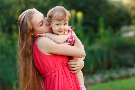 Young mother hugging her little girl in green parkの写真素材