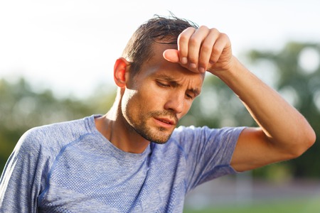 Tired athlete wiping sweat from forehead with back of his handの写真素材