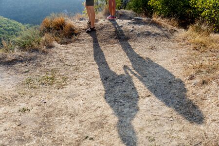 Shadow of two people holding hands on a hill with the sun-scorched grassの写真素材