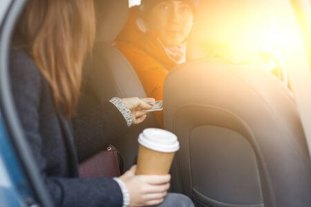 Brunette sitting in taxi with Coffey in hands sends cashfor passage driverの写真素材