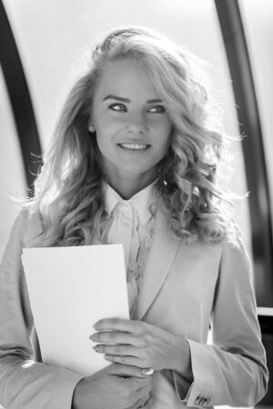 Black and white portrait of young beautiful smiling business lady holding paper. Portrait indoorの写真素材