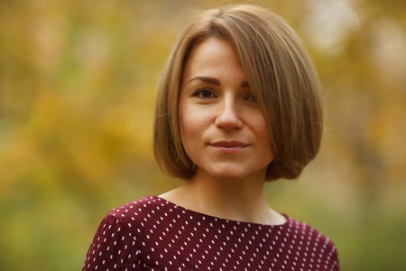 Close-up outdoors portrait of beautiful caucasian woman with brown hair of medium length. Autumn themeの写真素材