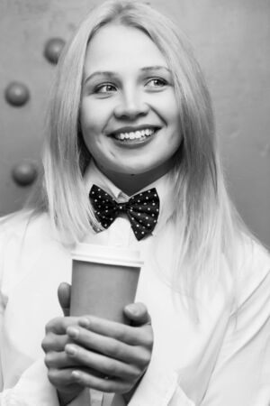 Portrait of beautiful girl with paper cup of coffee in white shirt. black-white photoの写真素材