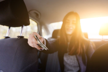 Young girl with long hair gives money for travel sitting in taxi