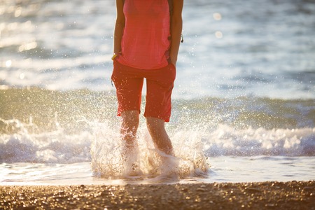 Young woman in red shorts jumping at seasideの写真素材