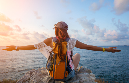 Young sports tourist girl enjoing beautiful views of the sea on sunny warm day. Portrait from the back with scenic sea views. Image with lens flare effectの写真素材