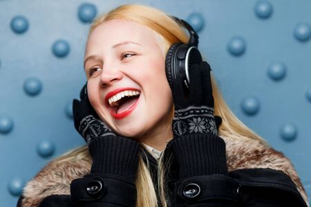 Ginger happy girl in headphones enjoying music at blue wallの写真素材