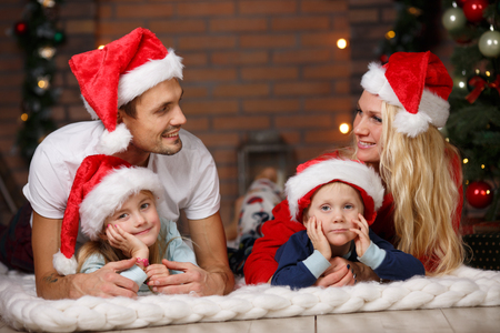Happy family lying on soft rug near Christmas treeの写真素材