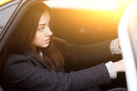 Beautiful brunette sitting in yellow taxi in afternoonの写真素材