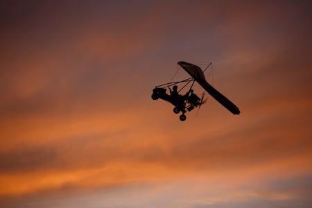 Hang glider flying in red and pink sky at sunsetの写真素材